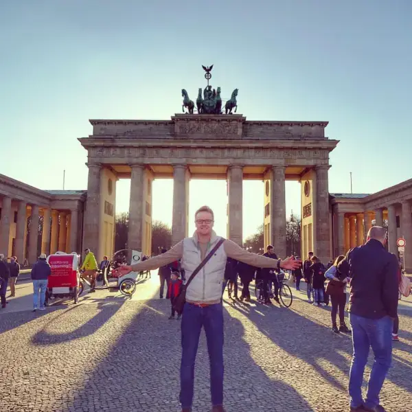 Owain with arms outstretched in front of the Brandenburg Gate in Berlin