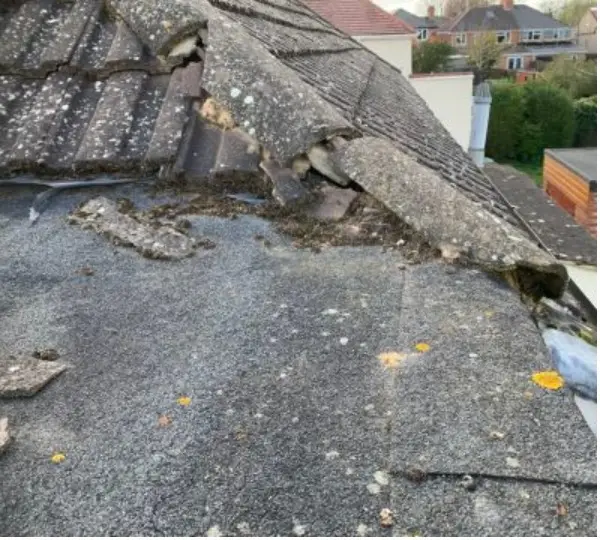 Loose felt and broken tile debris on the flat roof