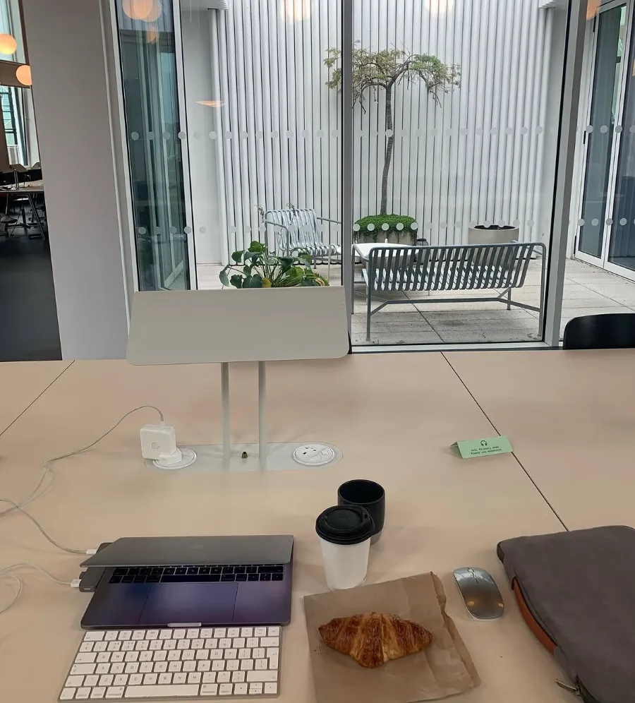 Owain’s laptop, coffee and croissant on a desk at Bureau Club in Greenwich, London